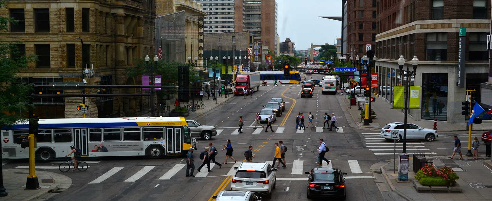 Minneapolis intersection showing pedestrians, bikers and bus, light rail alongside cars.